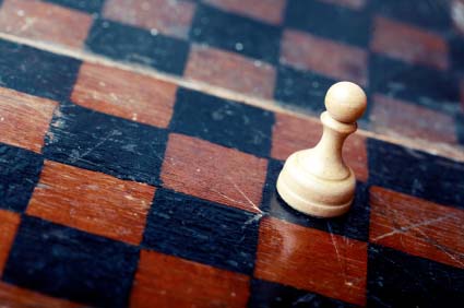 Close-up photo of the old wooden chessboard with white pawn as a symbol of the career.